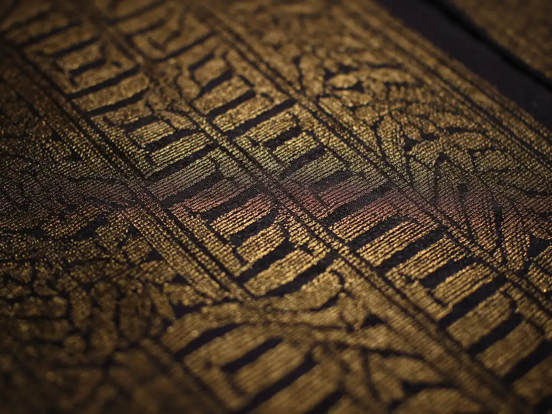 Macro of handwoven songket fabric, gold thread through deep indigo silk